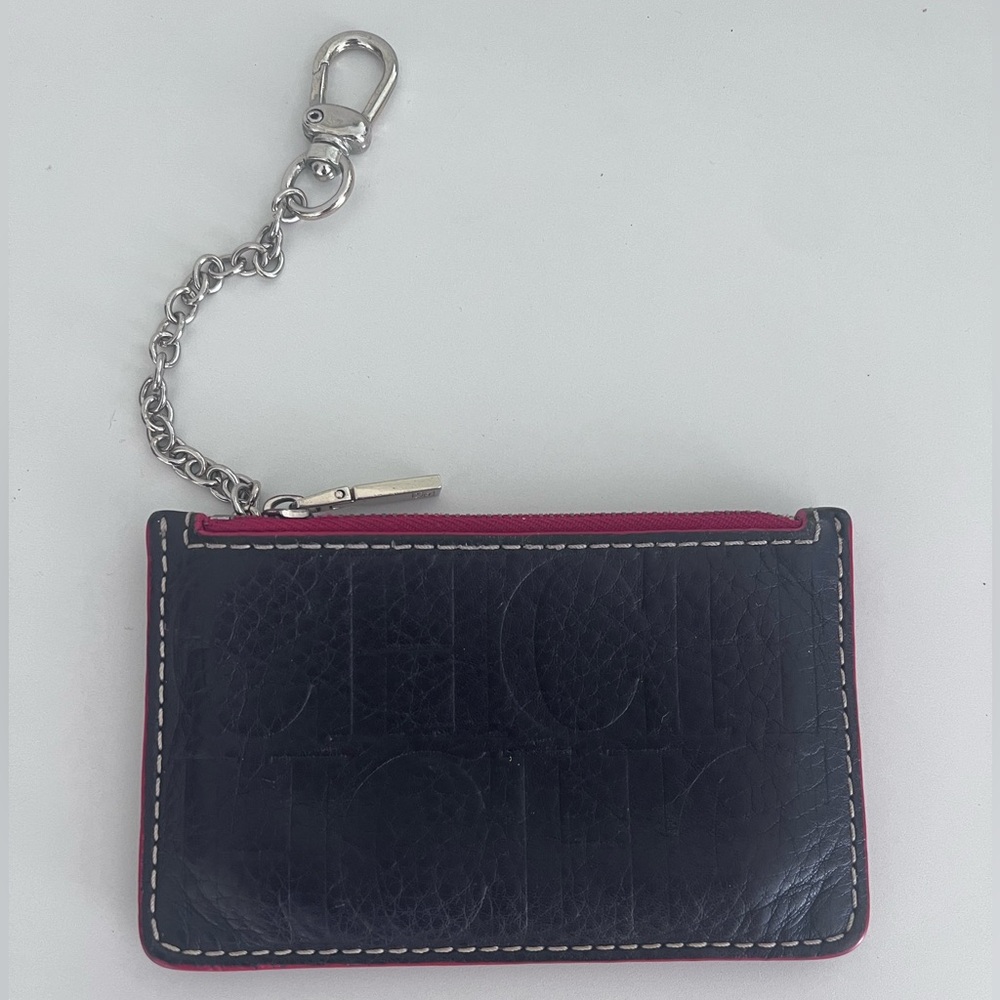 CH by Carolina Herrera small leather good. It is dark purple with a red zipper.